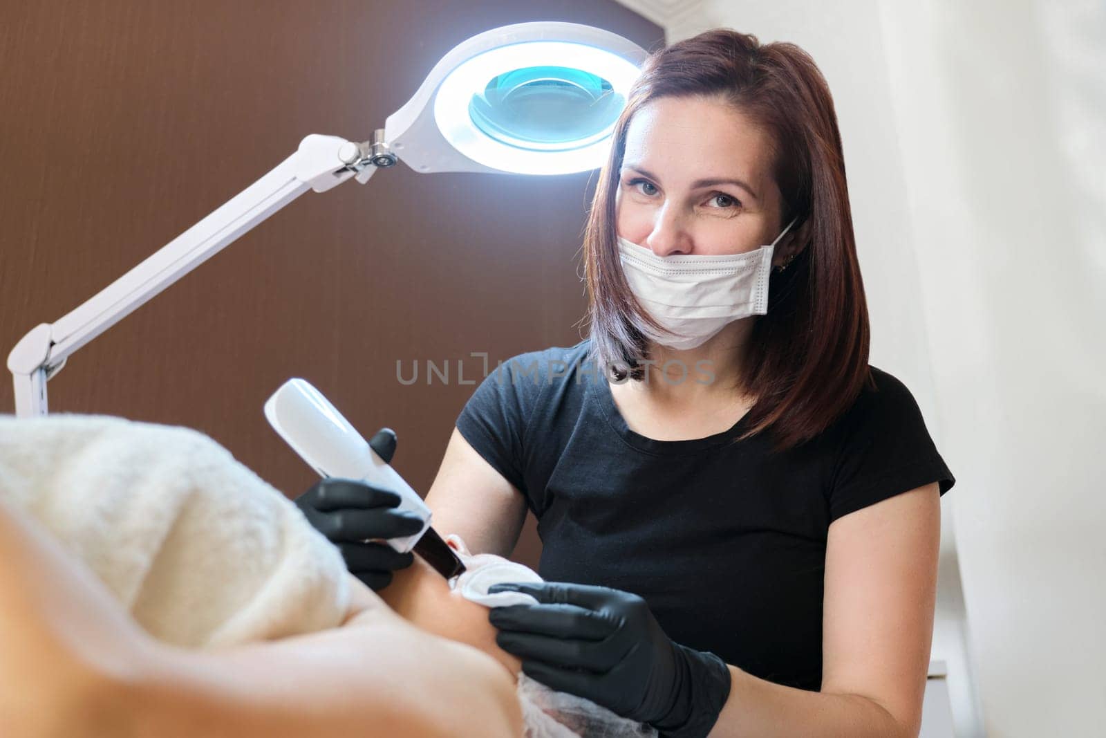 Portrait of beautician woman working with female patient at beauty clinic by VH-studio