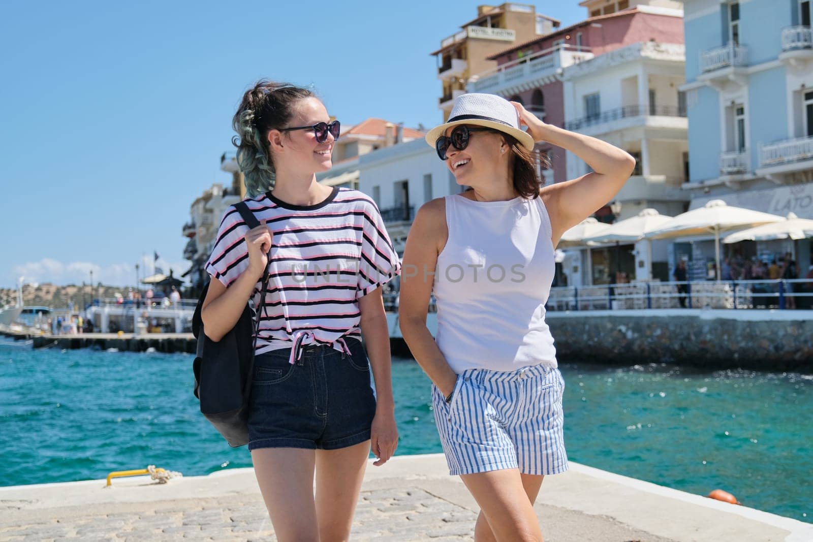 Traveling tourism to Europe Mediterranean, happy mother and daughter teenager walking, summer sea vacation. Greece Mirabello Bay, Agios Nikolaos
