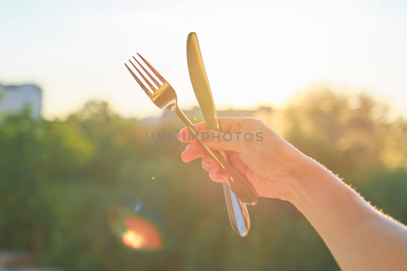 Steel metal shiny knife and fork in womans hand by VH-studio