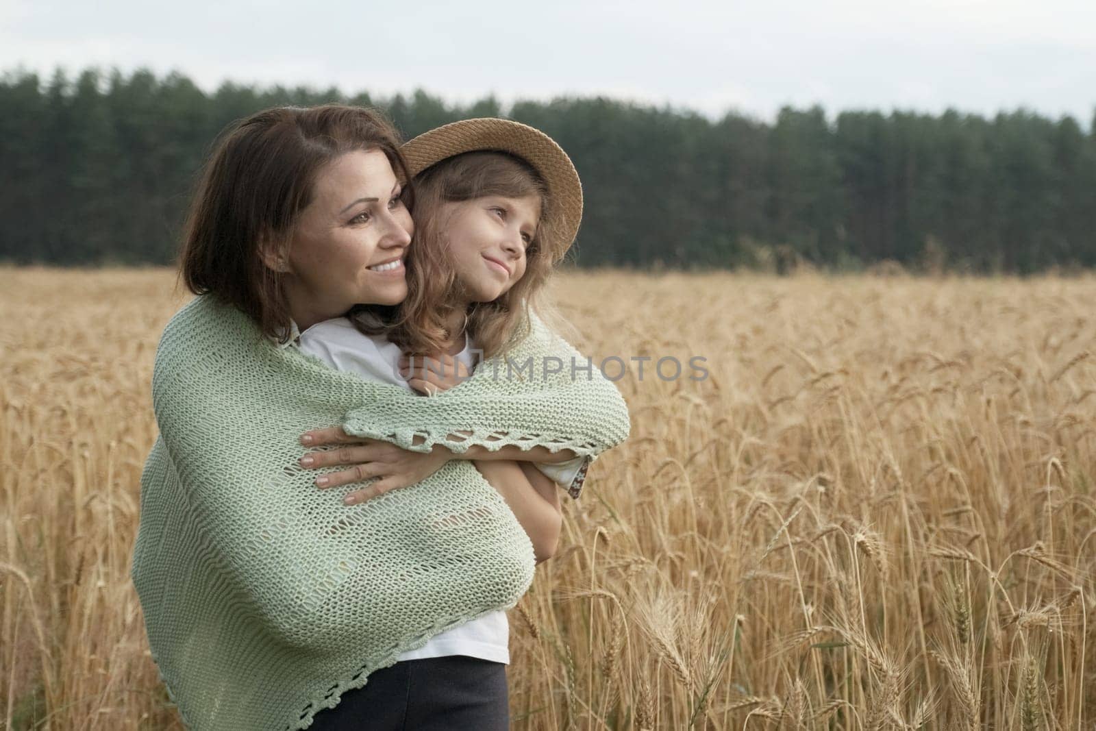 Mother hugging her little daughter, wheat field background by VH-studio