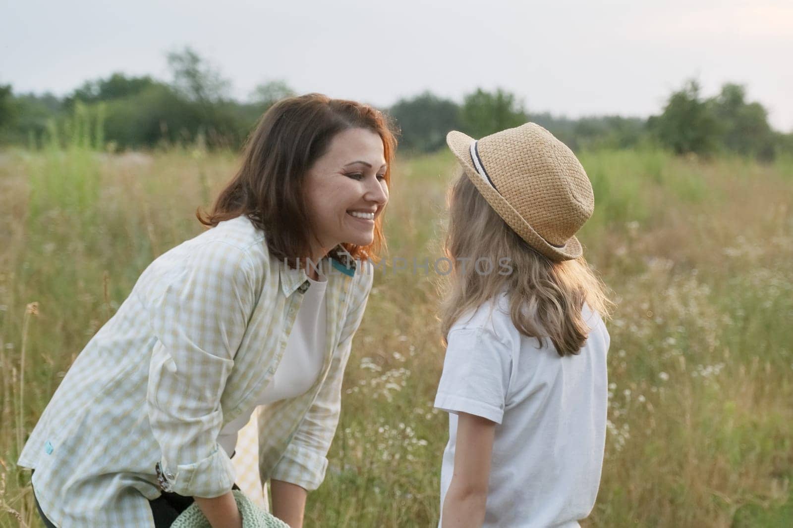 Smiling mother talking with child daughter, summer nature by VH-studio