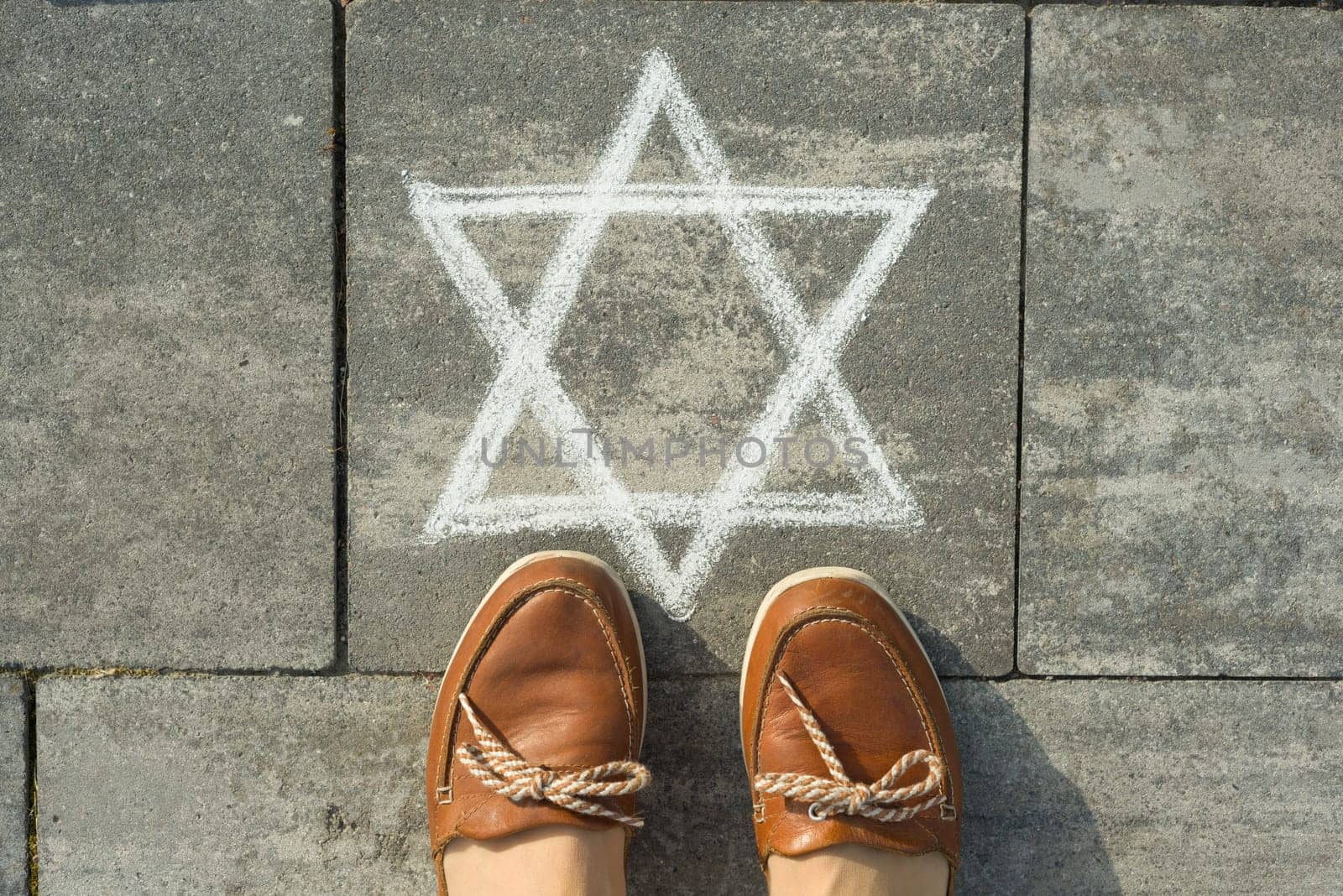 Female feet with abstract image of six pointed star, written on grey sidewalk by VH-studio