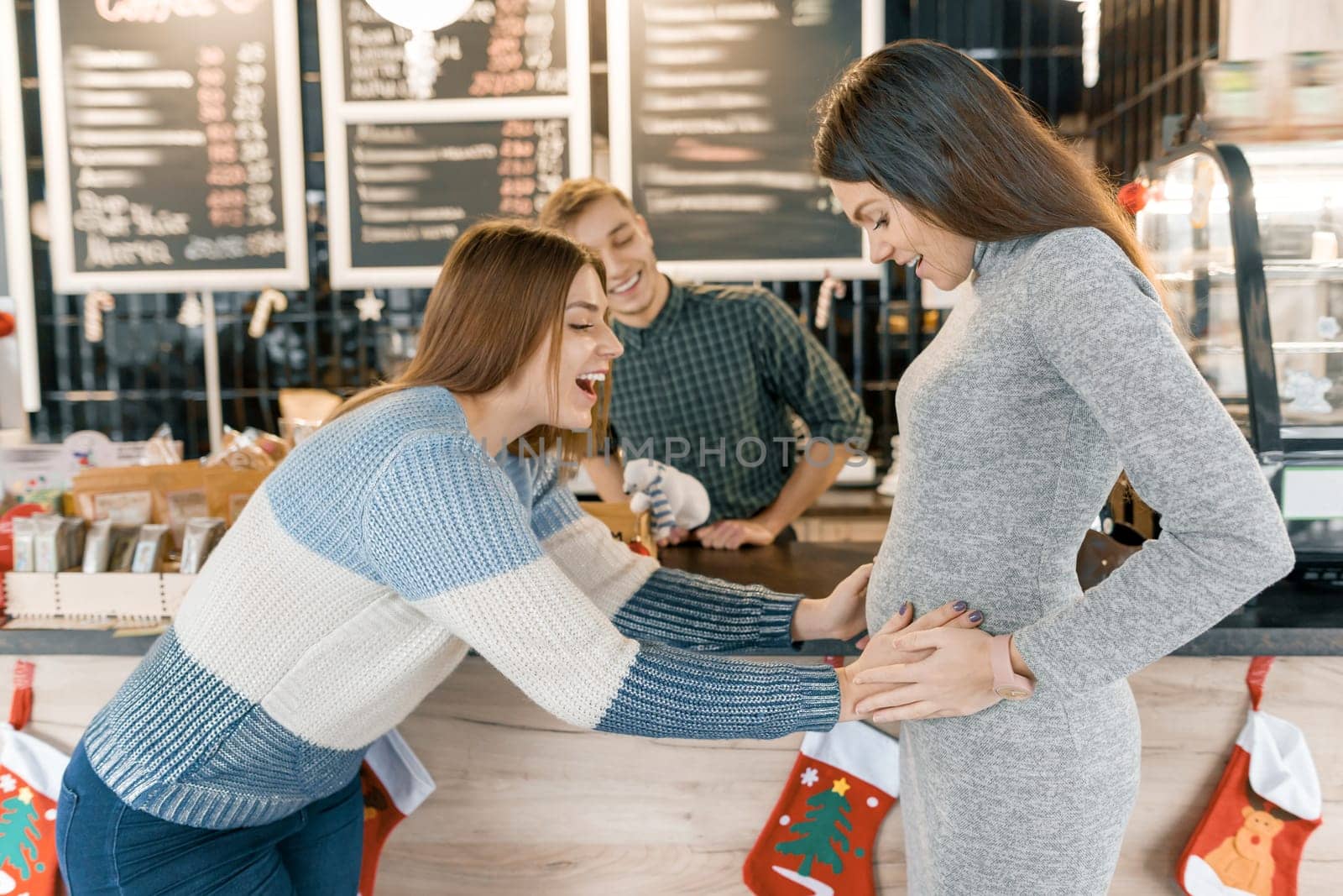 Pregnant woman who told her friends good news motherhood, girlfriend joyfully reacting, touches the belly