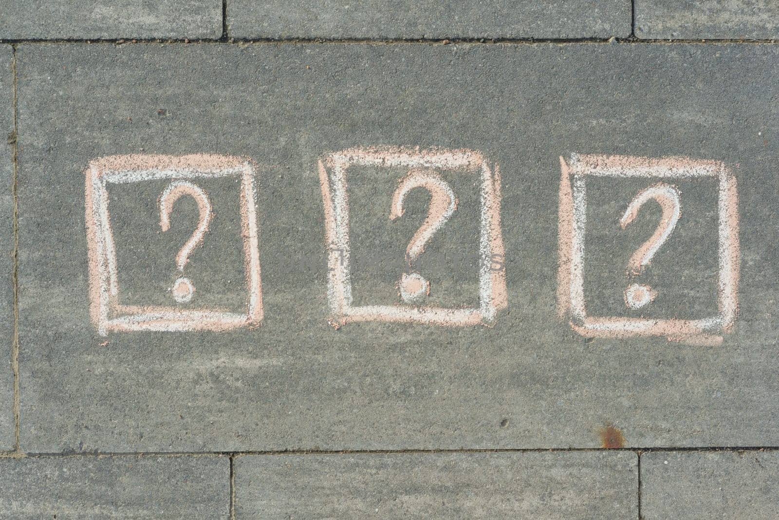 3 question marks painted on the grey sidewalk.
