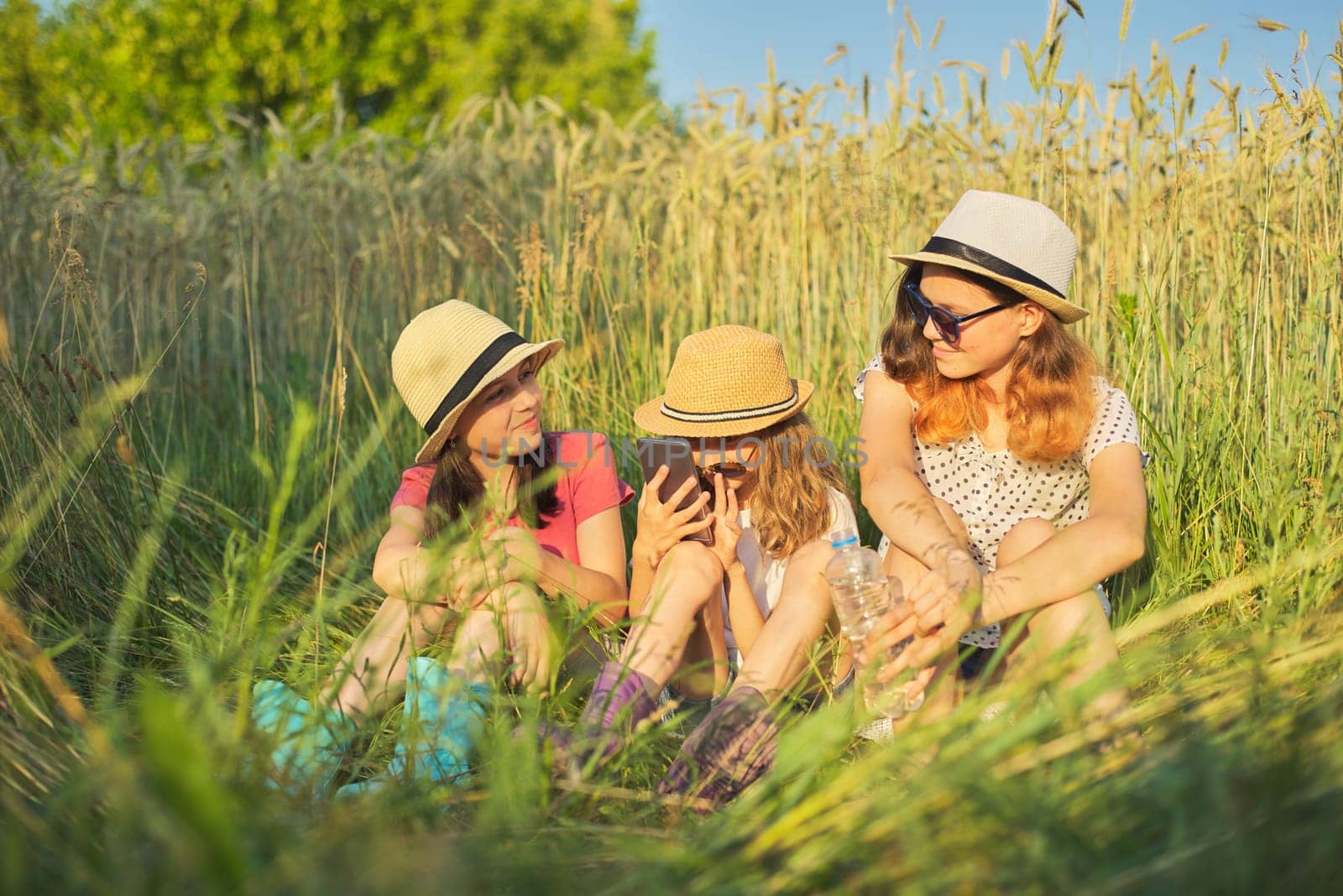 Portrait of three girls sitting and resting in grass by VH-studio