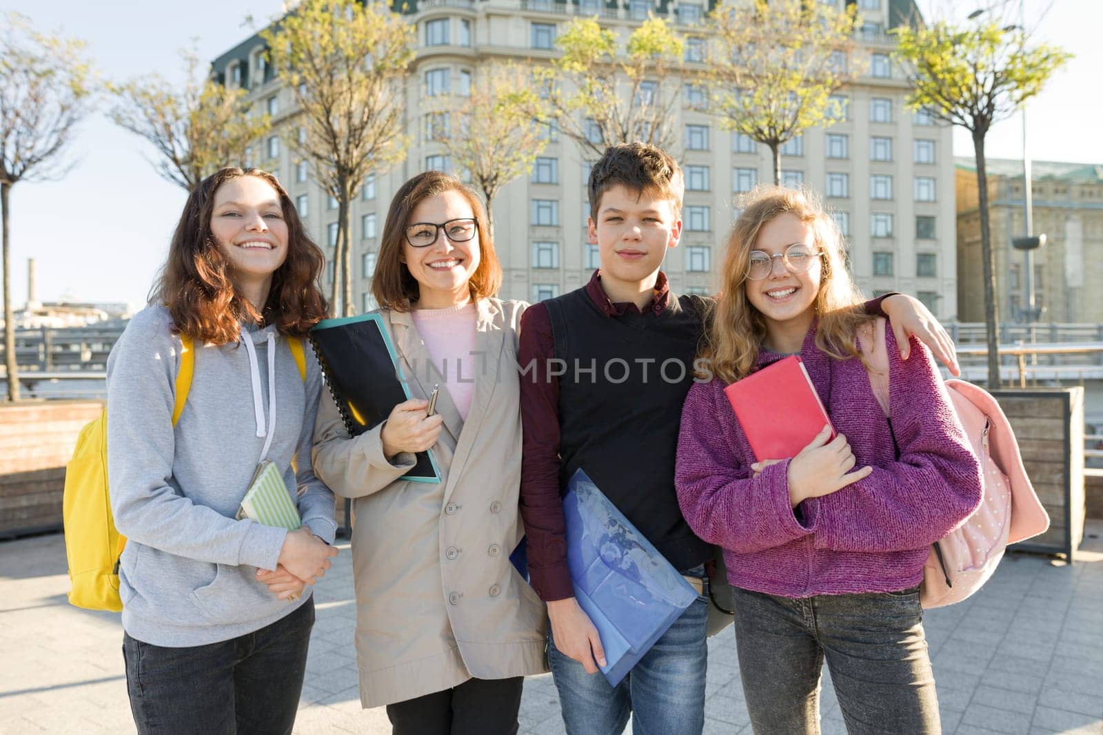Group of students with teacher, teenagers talking to a female teacher, outdoor portrait