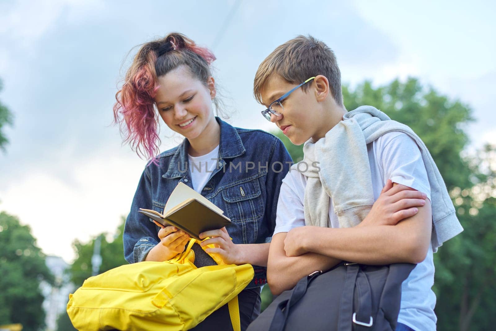 Outdoor portrait of two talking teenagers students by VH-studio