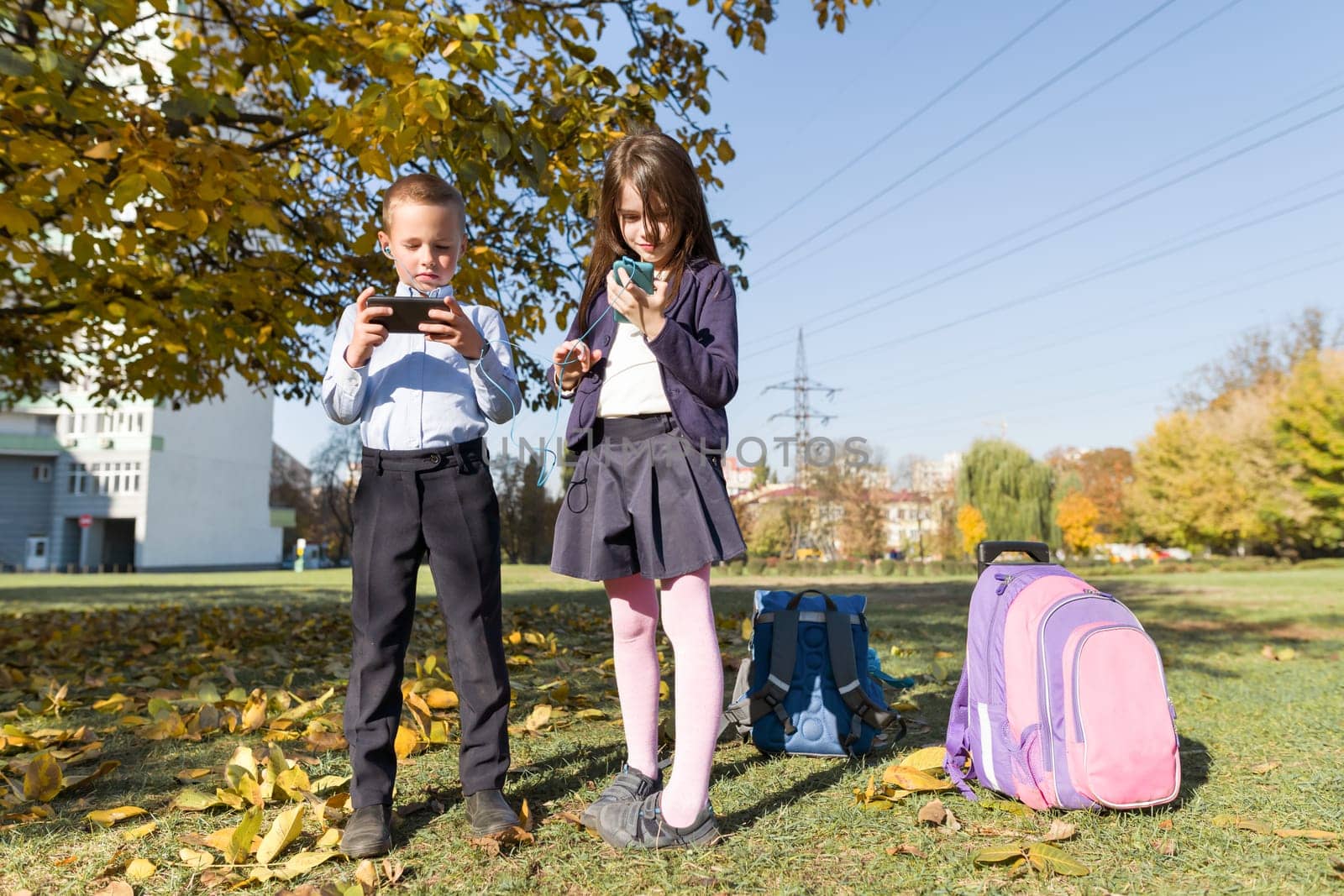 Two schoolchildren 7, 8 years old with mobile phones by VH-studio