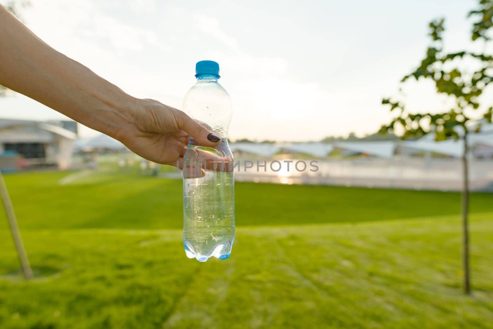 Bottle of water in female hand, copy space by VH-studio
