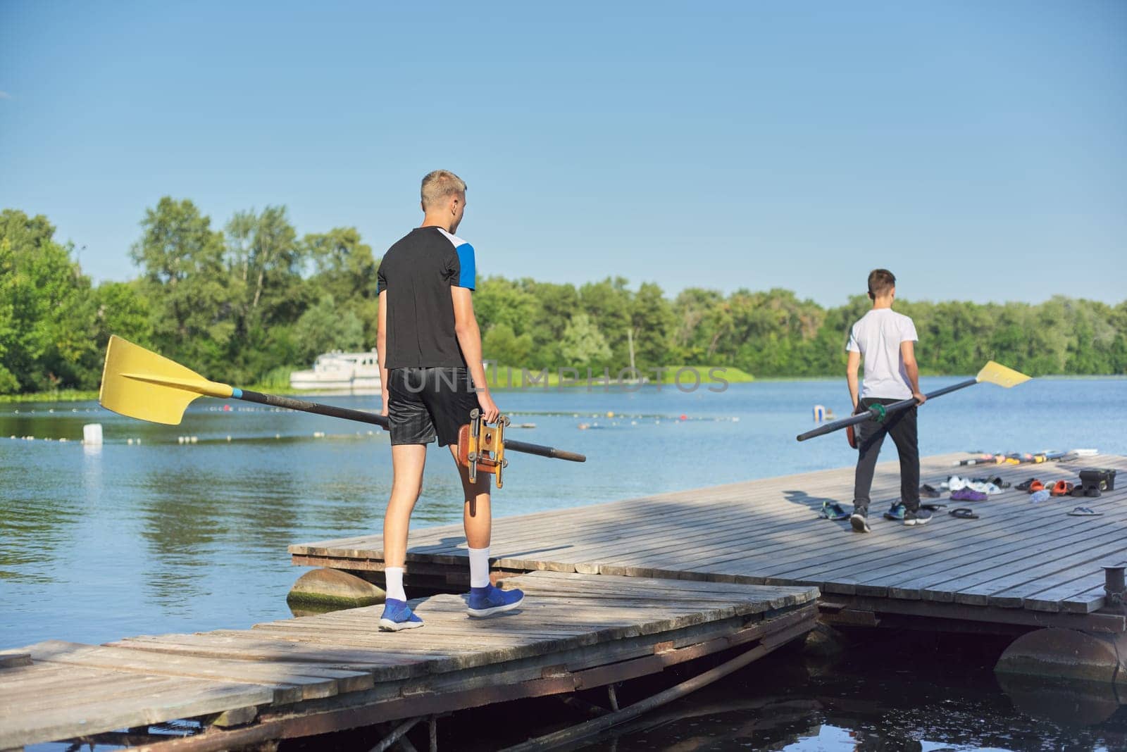 Boys teenagers walking with paddle for sport kayak boat, water sports, active healthy lifestyle of young males