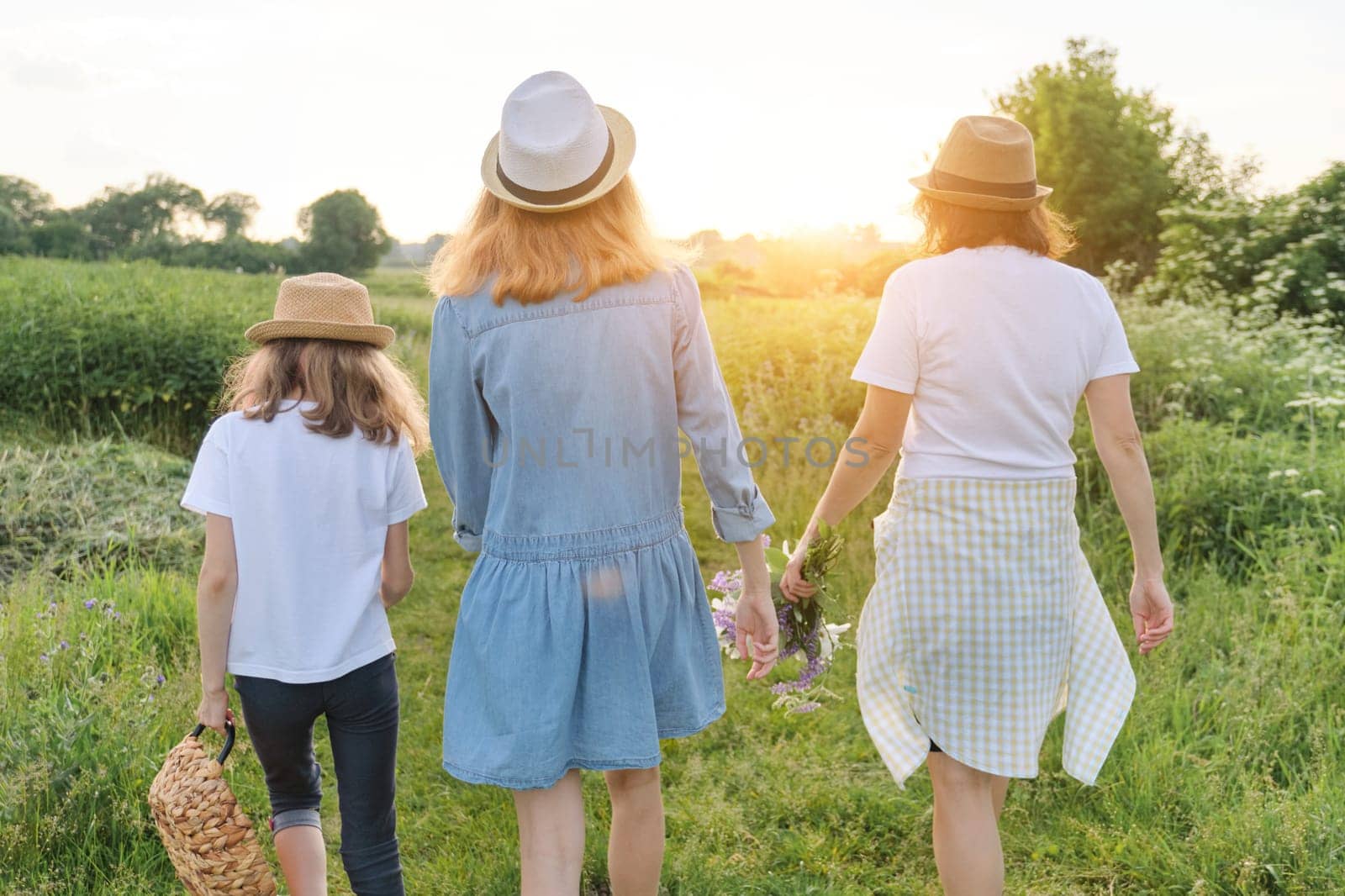 Mother with children two daughters walking along a country road, back view by VH-studio