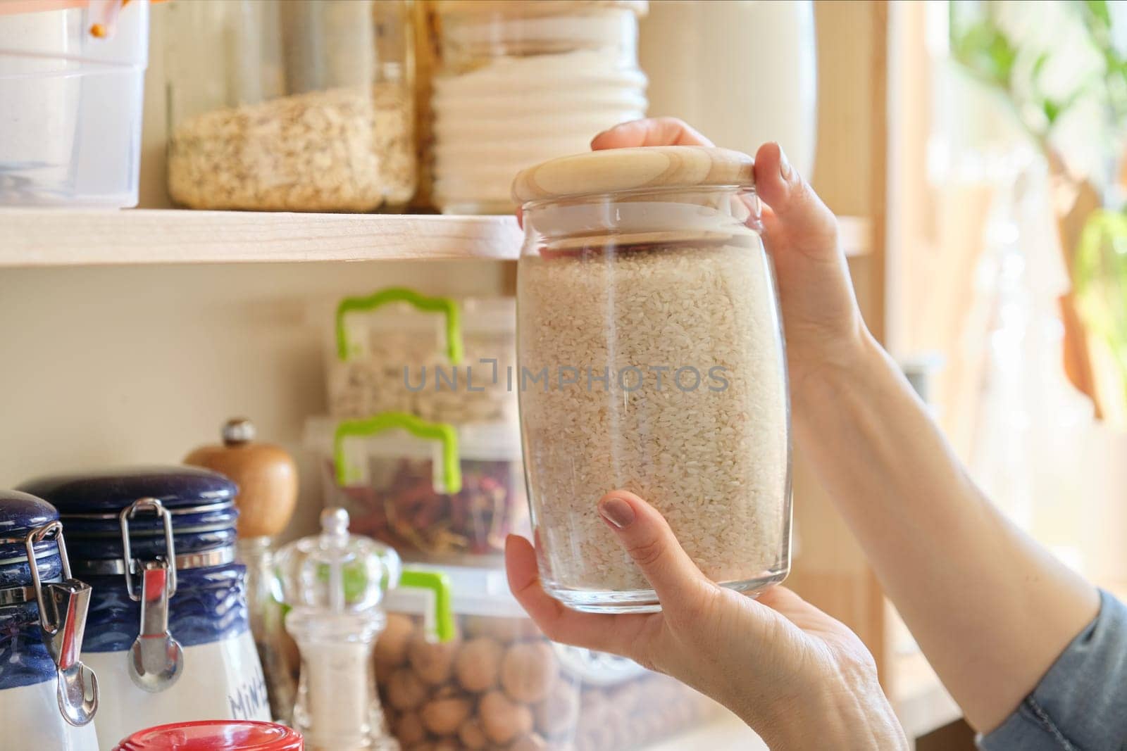 Food products in the kitchen storing ingredients in pantry. Woman taking jar of rice