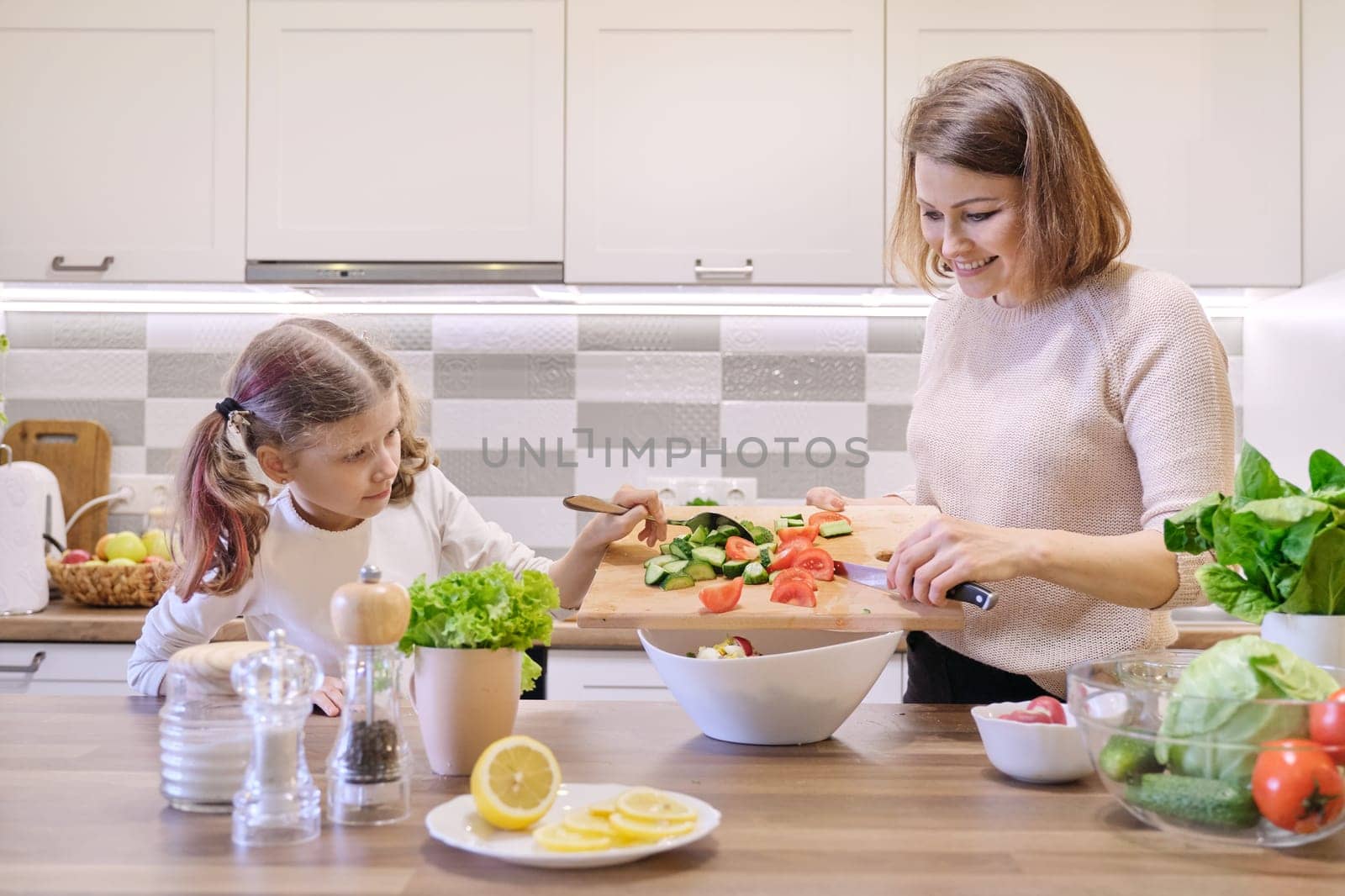 Mother and daughter child cooking together in kitchen by VH-studio