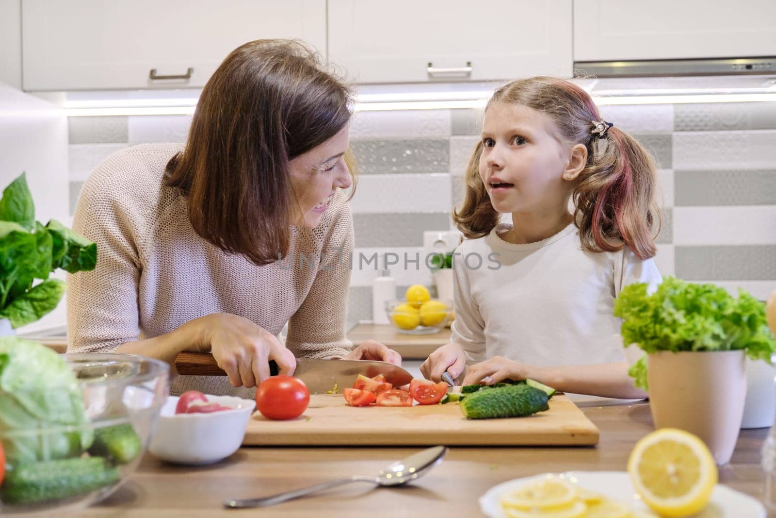 Mother and daughter cooking together in kitchen vegetable salad by VH-studio