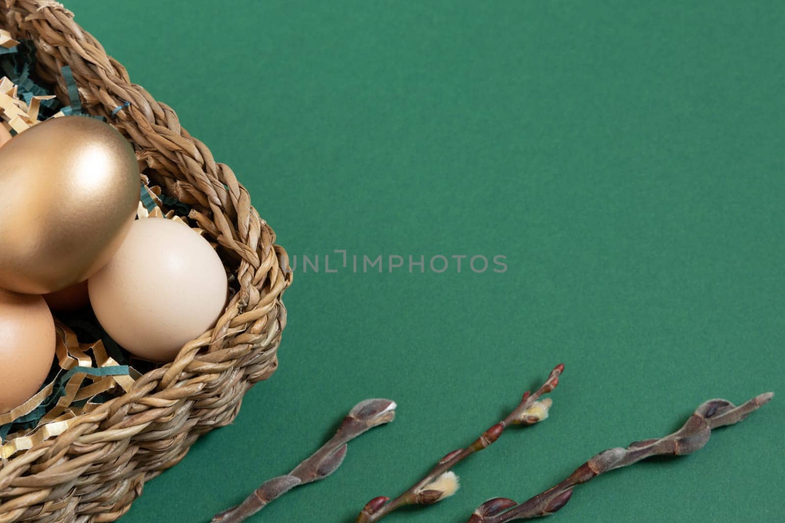 Easter eggs natural and gold in basket with paper filler . Branch of willow catkinsan. Light pastel orange background with copy space. by Ri6ka
