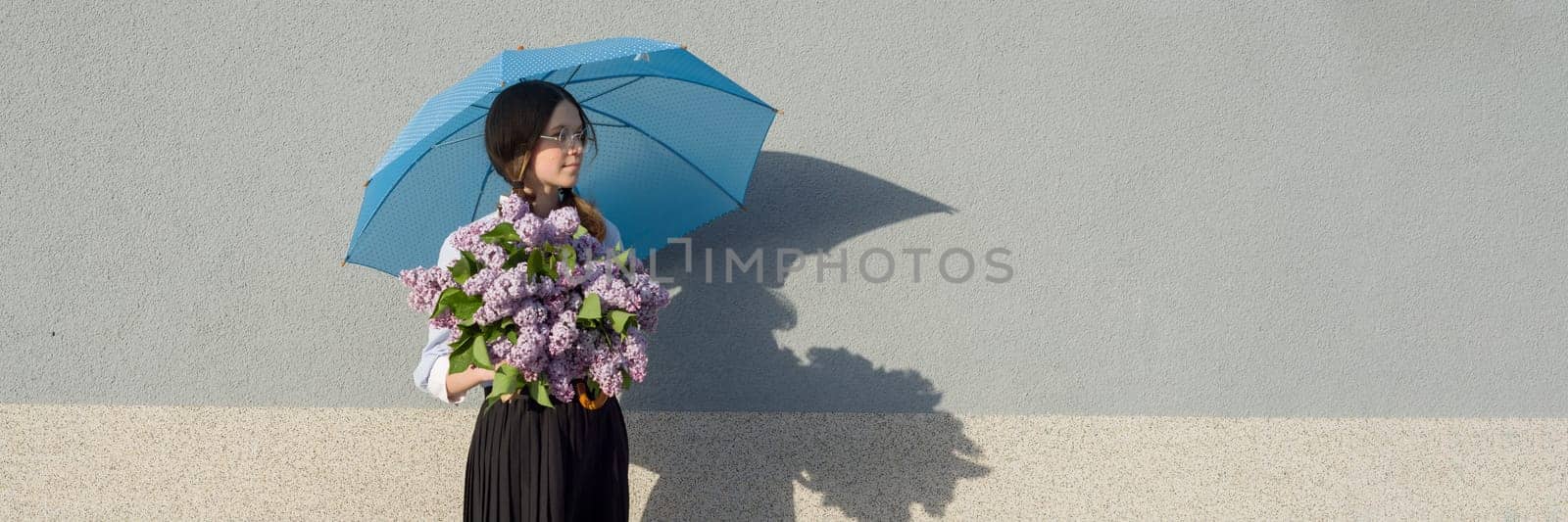 Profile portrait romantic teenage girl with bouquet of lilacs, with umbrella on gray wall background. Outdoor, copy space, panoramic banner.