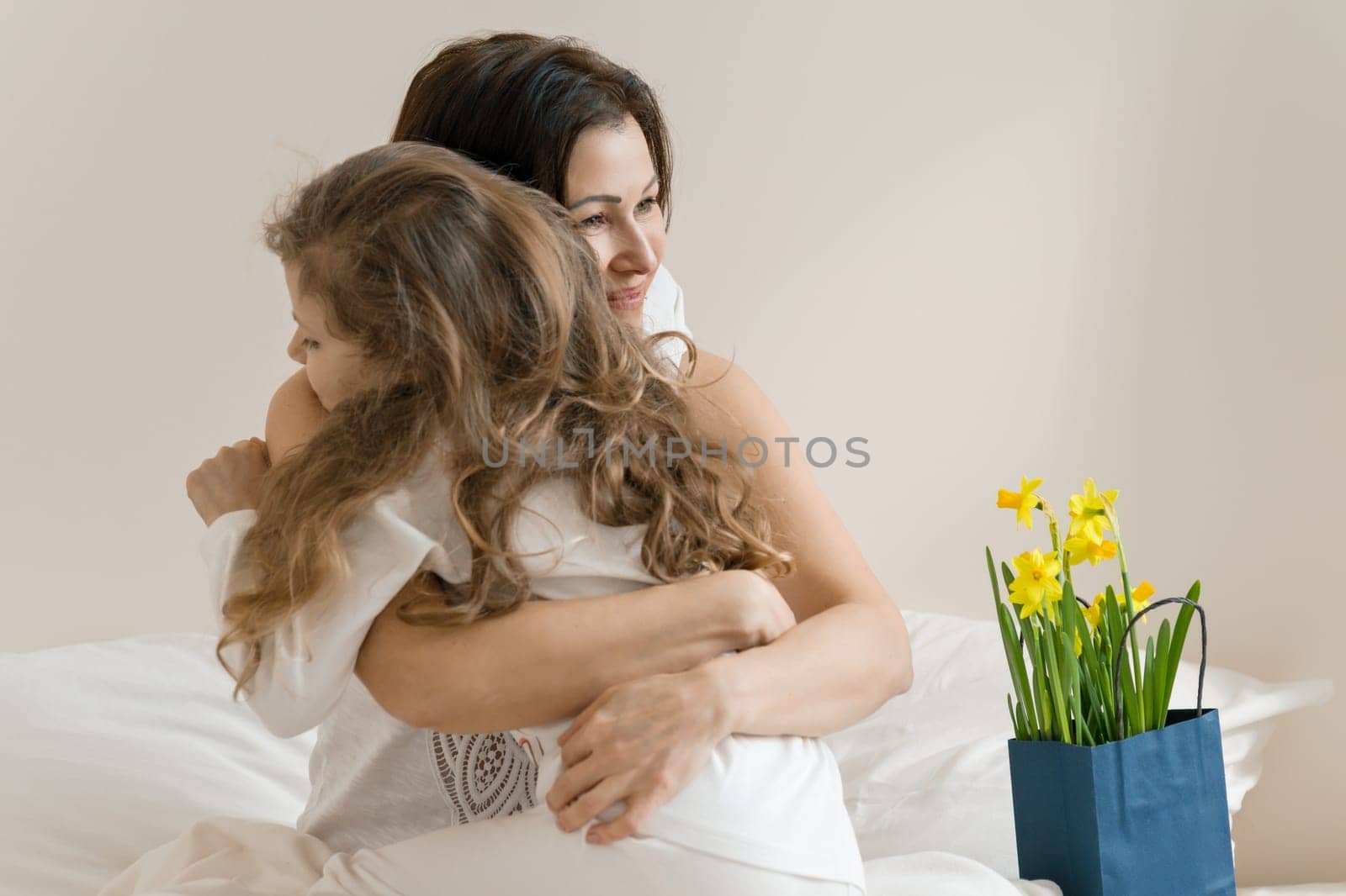 Mothers Day. Morning, mom and child in bed, mother hugging her little daughter. by VH-studio