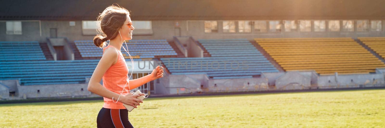 Beautiful teenage girl running in stadium, panoramic banner