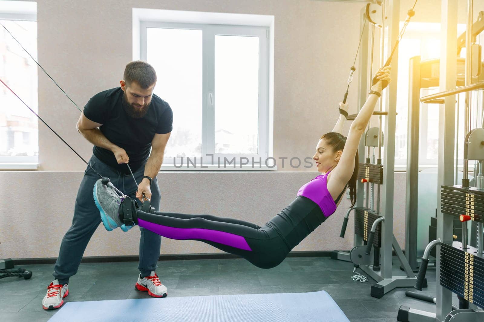 Young woman doing rehabilitation exercises with personal instructor using kinesi machine by VH-studio