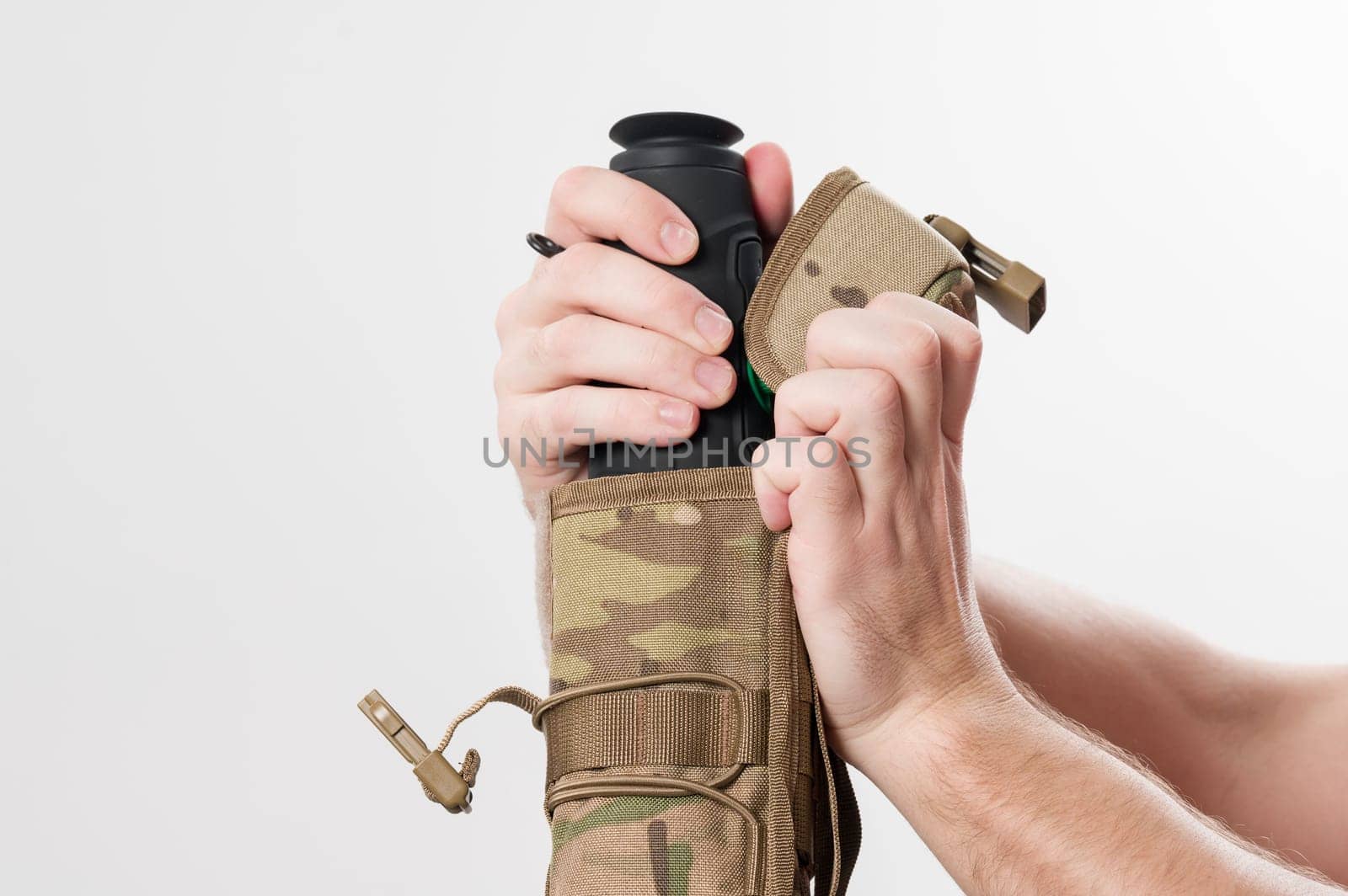 Military monocular in a case for storage and carrying, a man demonstrates a monocular in a protective case to a bag in pixels.