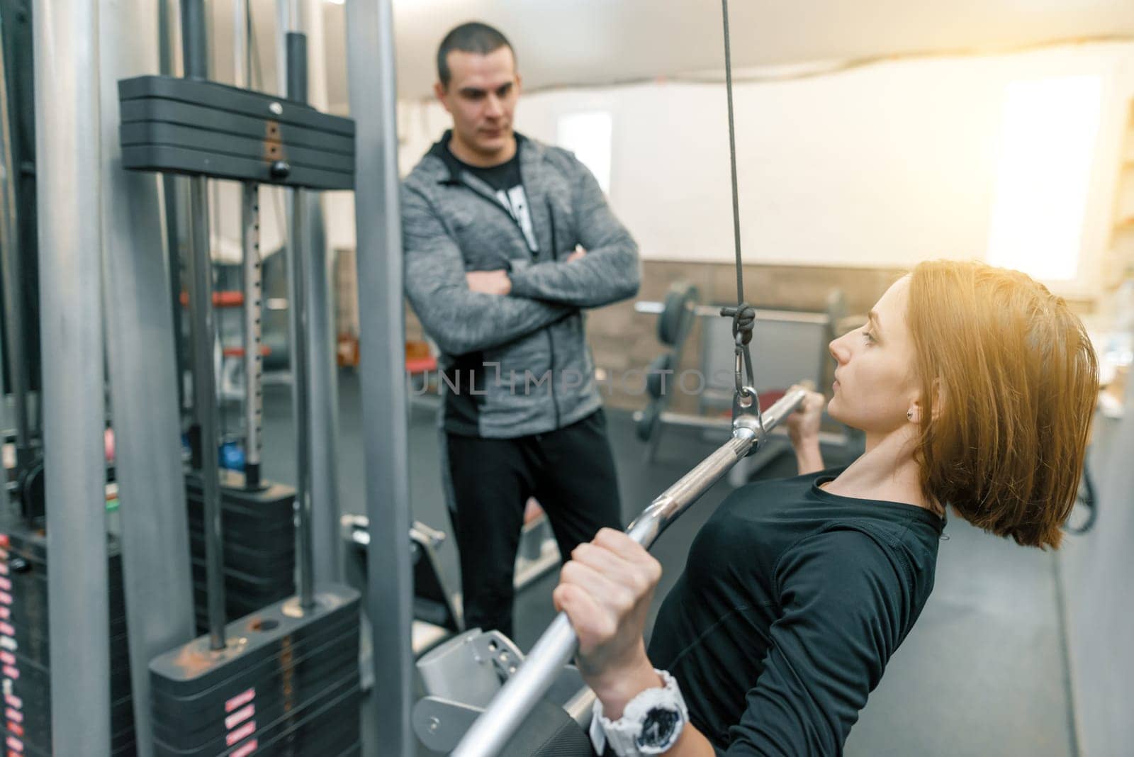 Young woman doing exercises with personal instructor in gym. Sport, athlete, training, healthy lifestyle and people concept by VH-studio