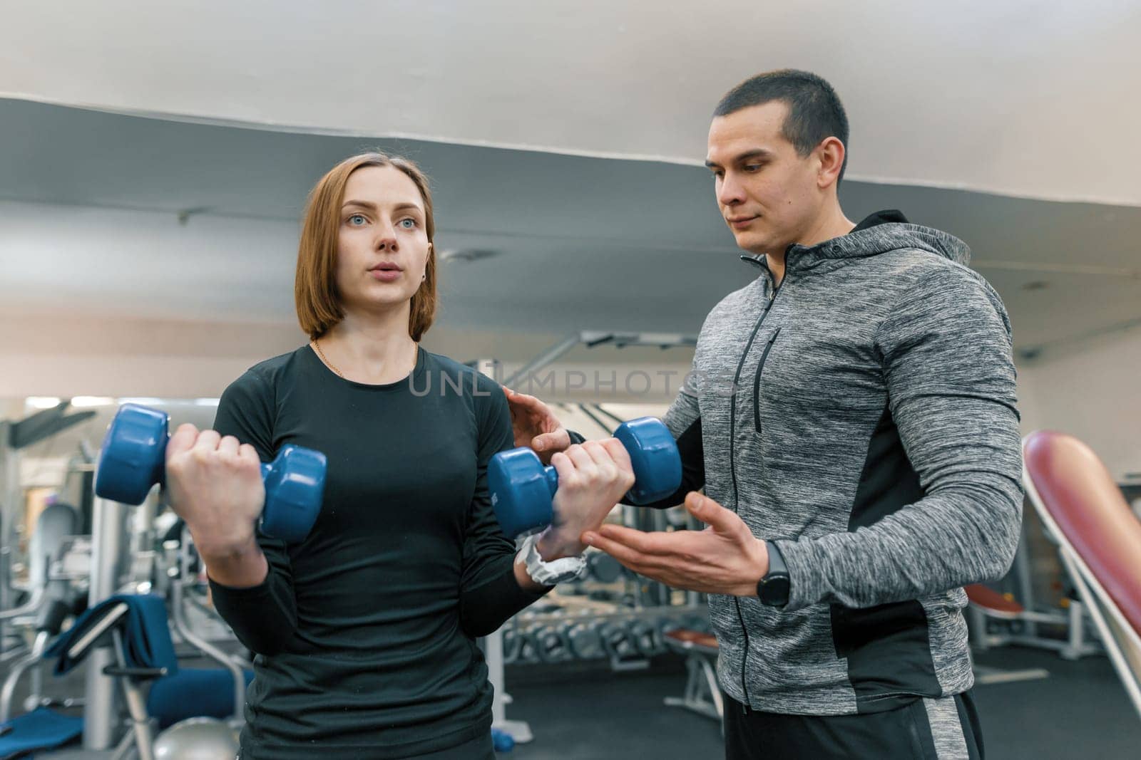 Young woman doing exercises with personal instructor in gym. Sport, athlete, training, healthy lifestyle and people concept.