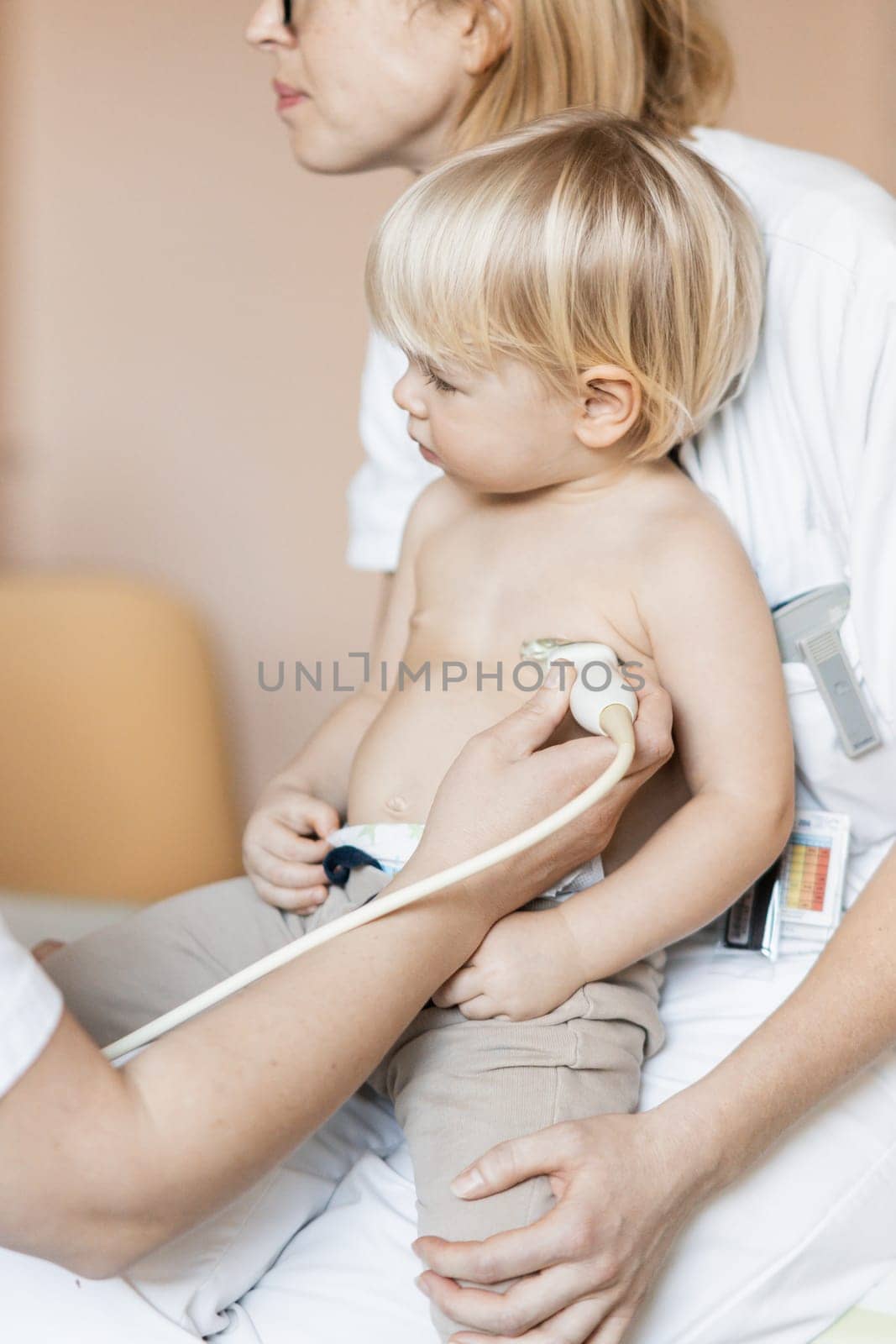 Small child being checked for heart murmur by heart ultrasound exam by cardiologist as part of regular medical checkout at pediatrician. by kasto