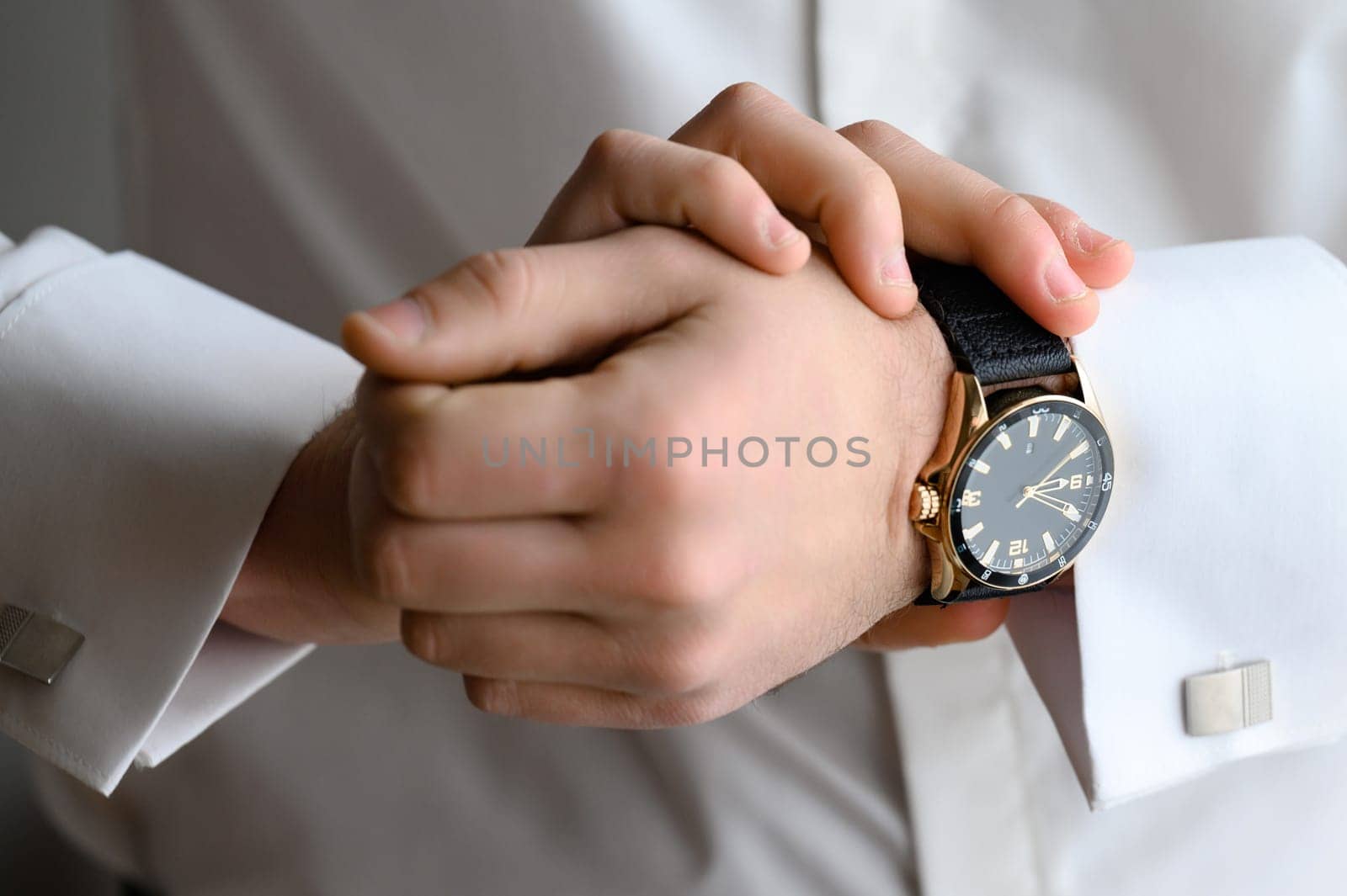 The morning of the groom on the wedding day before the wedding ceremony, the man adjusts the clock on his hand.