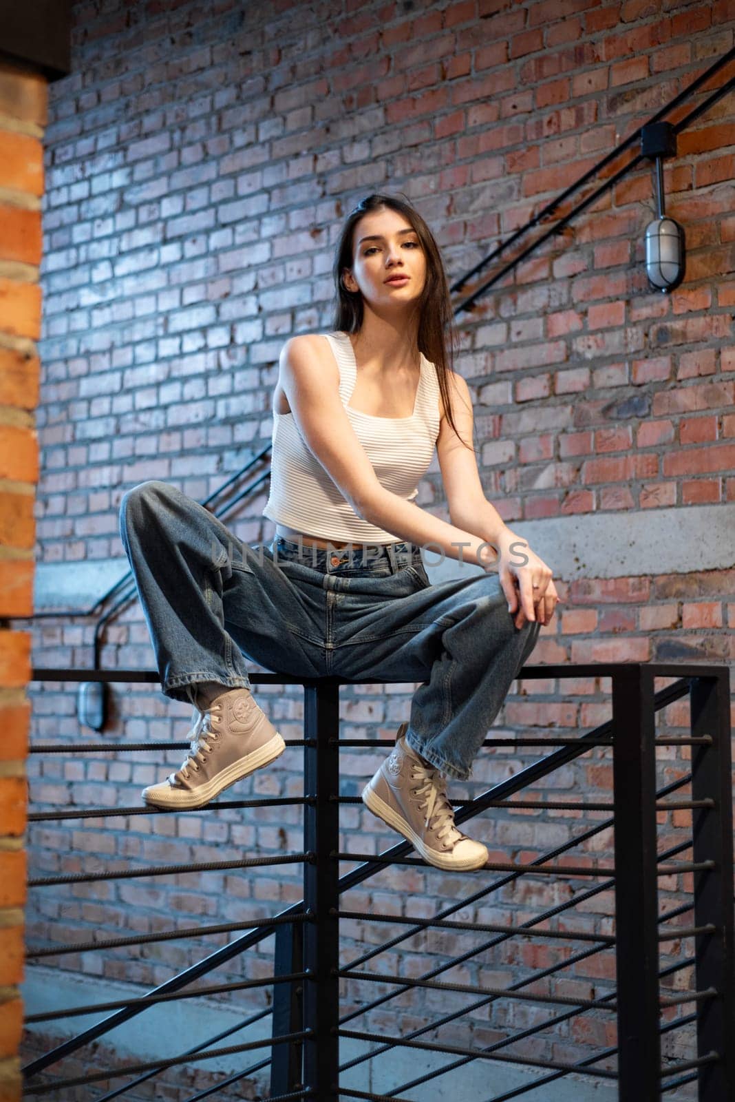 Young woman wearing casual denim jeans and white shirt posing in hall