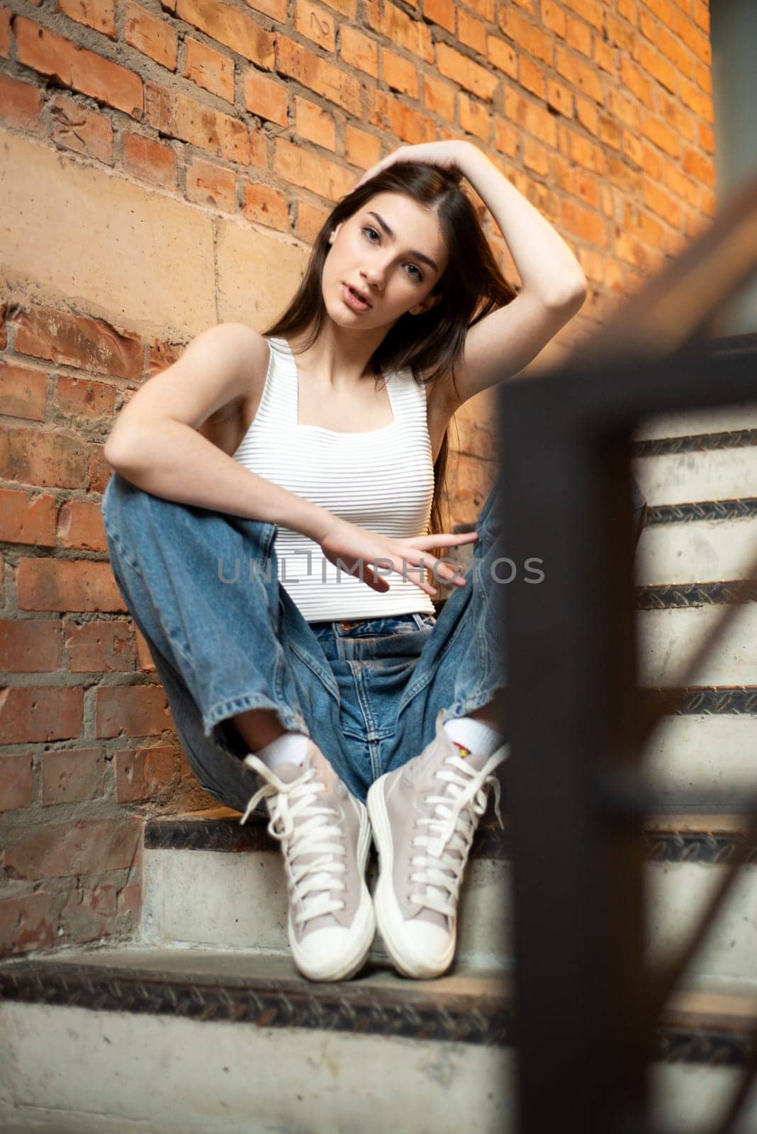 Young woman wearing casual denim jeans and white shirt posing in hall