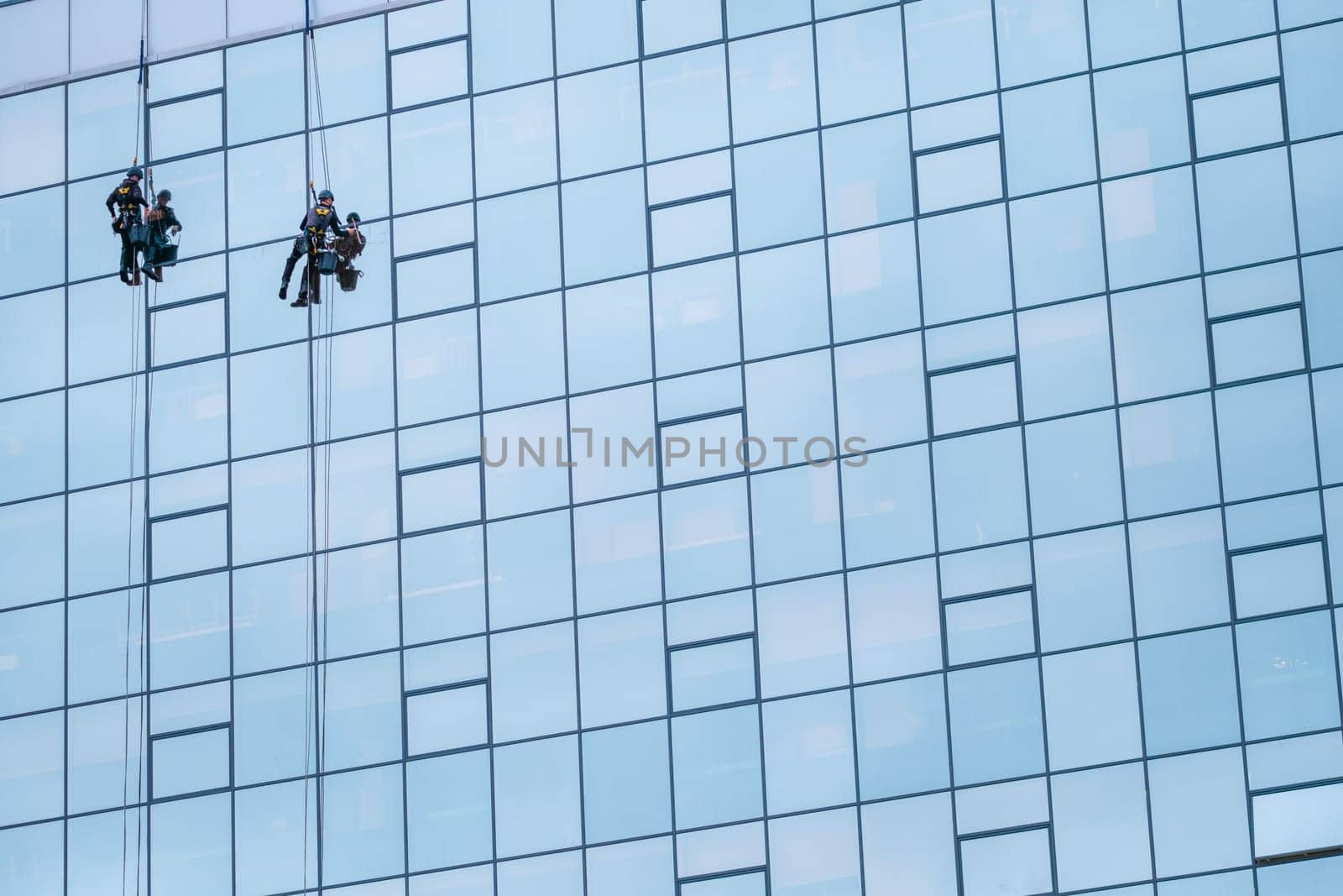 Two Worker Cleaning The Windows Of A High Rise Building Or Skyscraper, With Copy Space