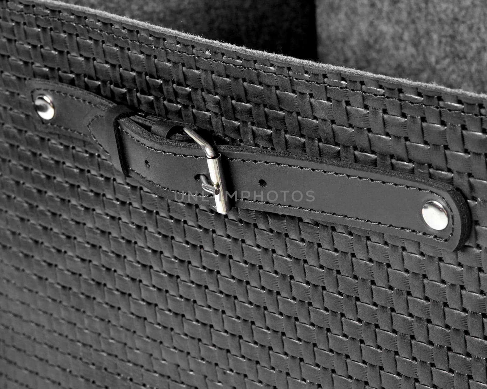 Closeup of black leather woven box with strap handle on rivets with buckle by nazarovsergey