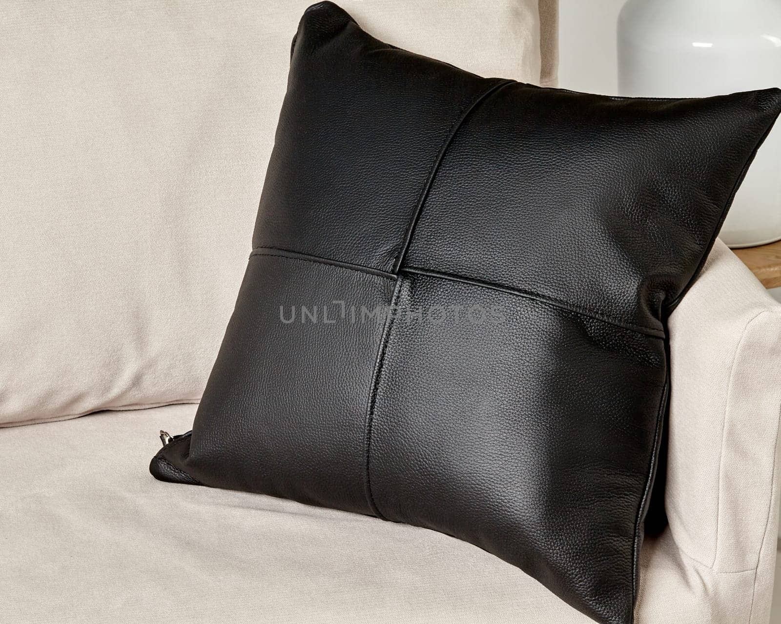 Black leather pillow with detailed stitch line on beige couch by nazarovsergey