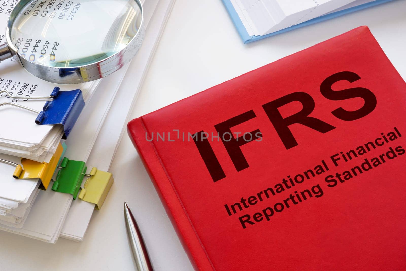 A stack of papers and a book IFRS International Financial Reporting Standards. by designer491