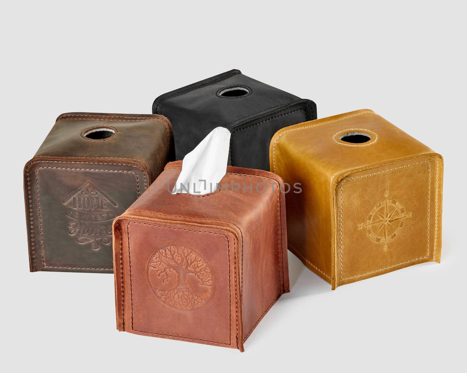 Various colored leather tissue box covers with embossed designs, isolated on white background. Stylish artisanal home decor item