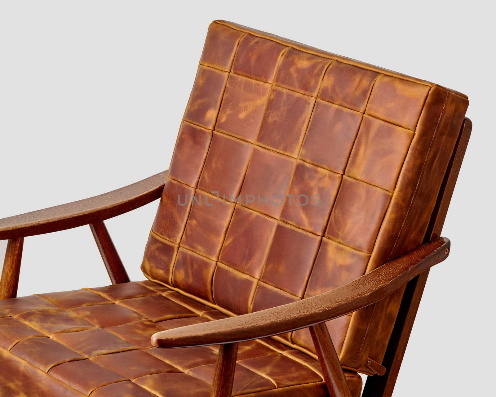 Distinctive armchair featuring patchwork design of smooth brown leather pieces combined with sleek wooden frame, showcasing blend of artisanal charm and modern elegance