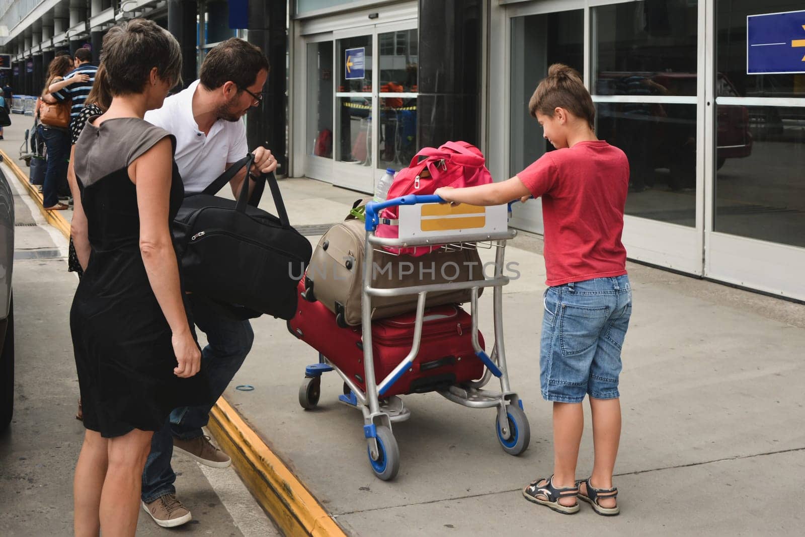 Family loading suitcases on a wheelbarrow at the airport