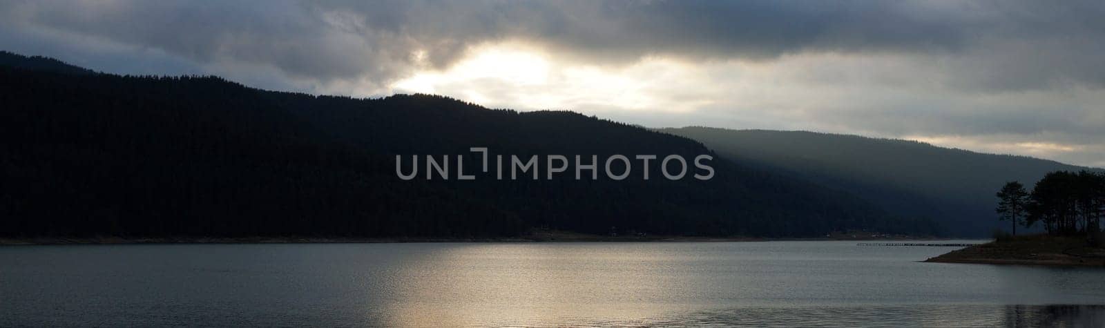 mountain lake at sunset in cloudy weather, horizontal panorama.