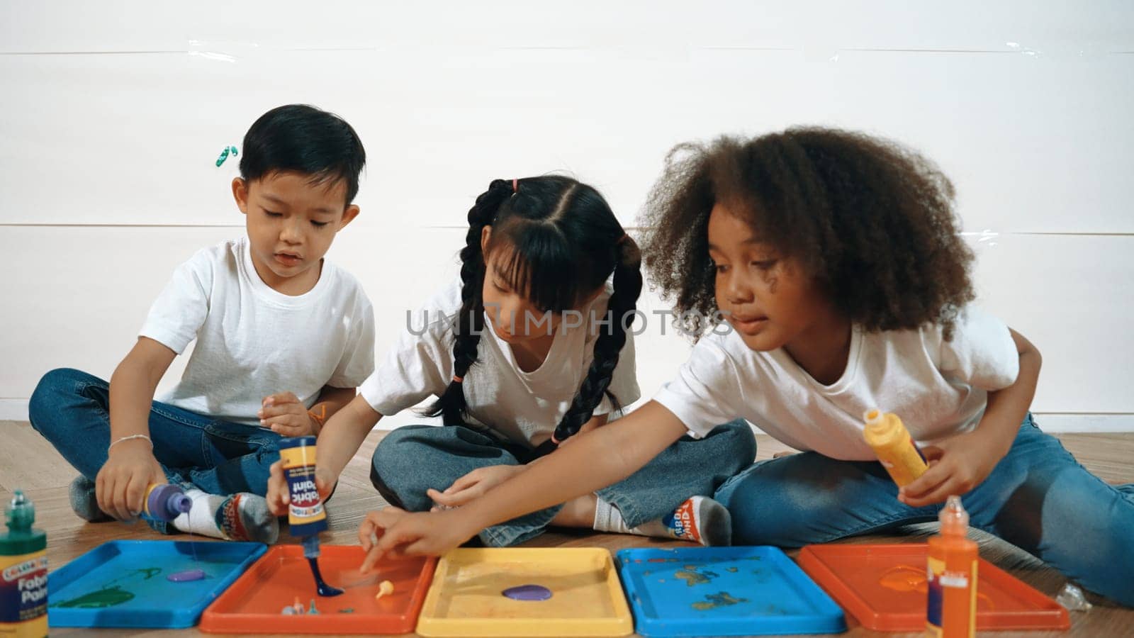 Group of diverse young student mixing color while sitting together. Happy multicultural children prepared mixed to playing and creating new artwork at art lesson. Creative activity concept. Erudition.