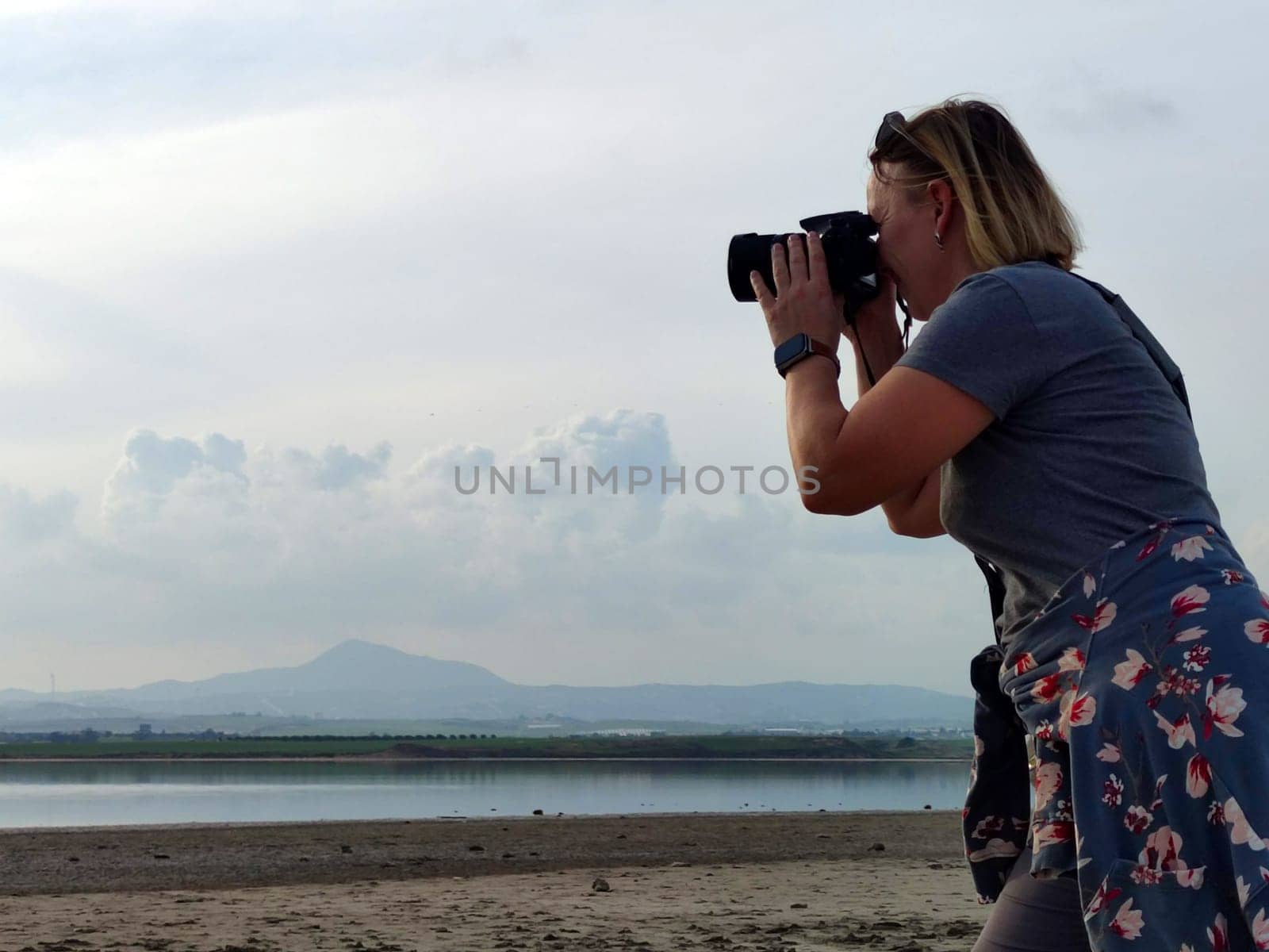woman traveler taking pictures of mountain lake by Annado