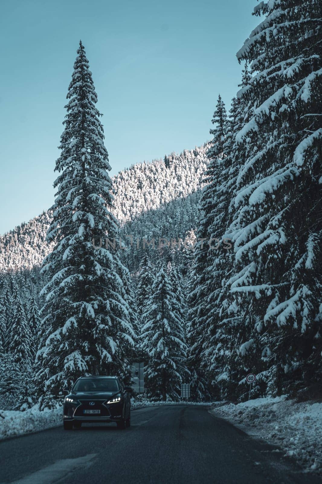 Winter sunset landscape with asphalt road through pine forest in Low Tatras, Slovakia