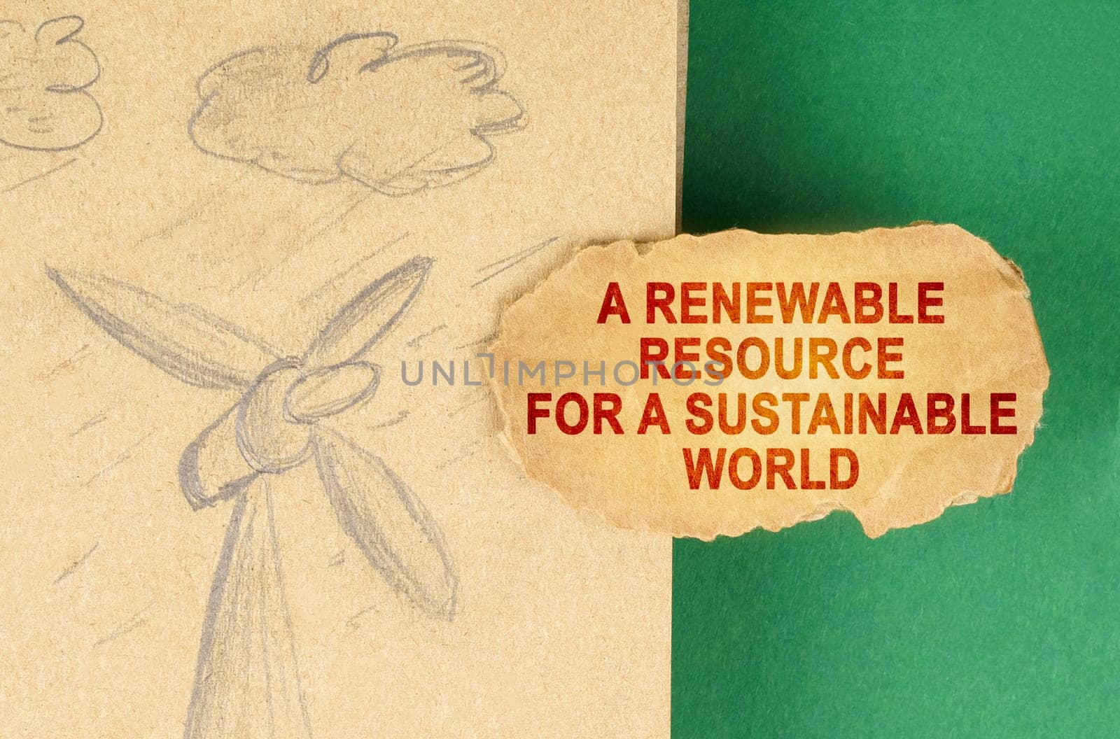 Alternative energy concept. On a green surface there is a drawing with a wind generator and a cardboard with the inscription - a renewable resource for a sustainable world