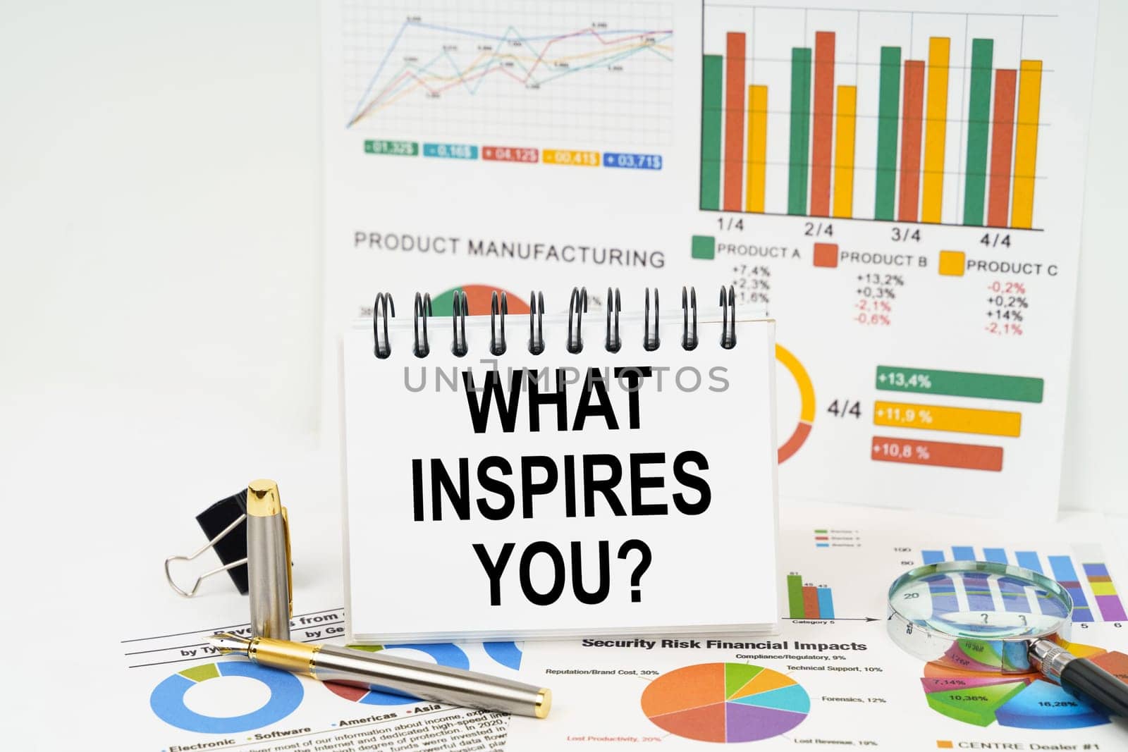 Business concept. On the table are reports with graphs and a notepad with the inscription - WHAT INSPIRES YOU