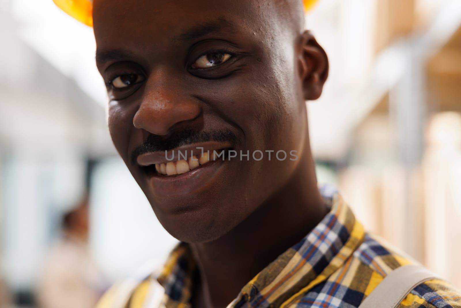 Young african american smiling storehouse worker looking at camera with positive facial expression. Man working in delivery service industrial storage room close up portrait