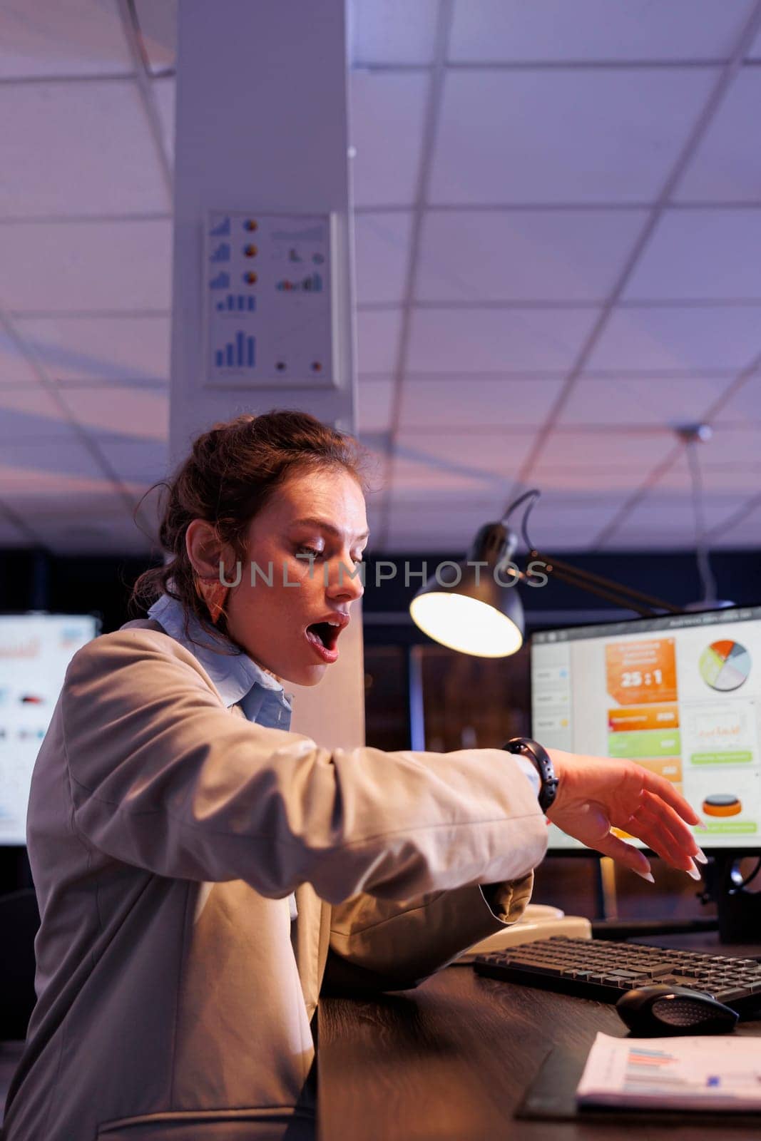 Businesswoman checking time on wristwatch, working overtime at financial investment plan to increase company profit. Executive manager analyzing marketing graphs in startup office
