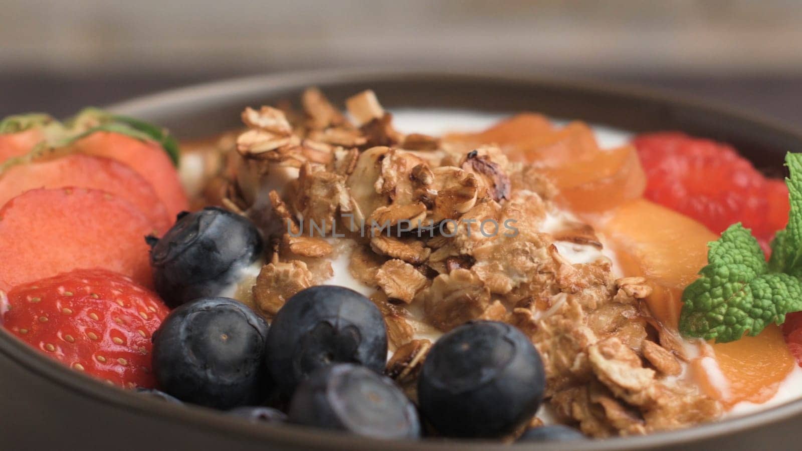 Yogurt with baked granola and berries in small bowl strawberries blueberries. Granola baked with nuts and honey for little sweetness. Slide from left.