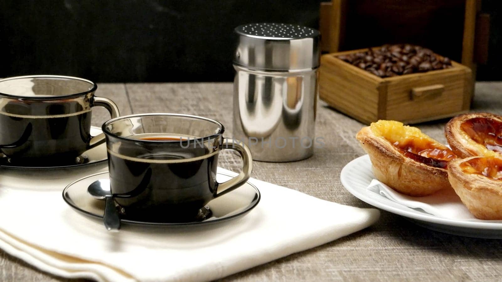 Pasteis de Nata or Portuguese Custard Tarts with black coffee on wooden table.