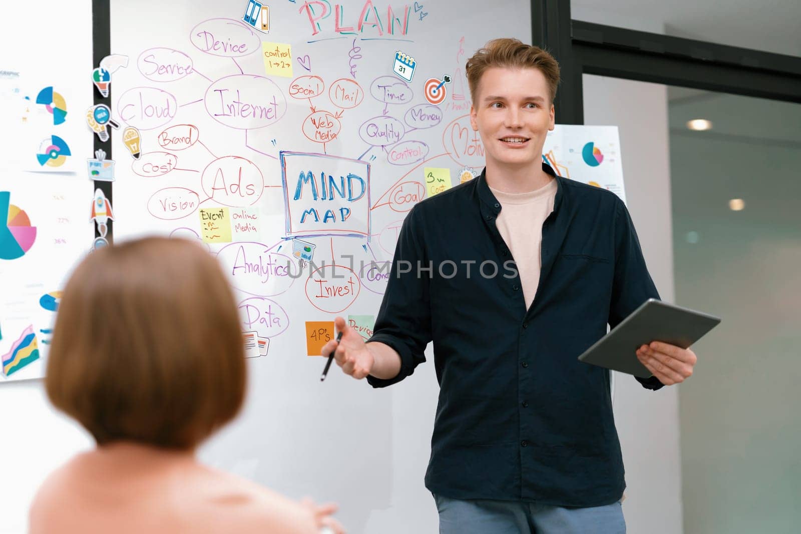 Professional male leader presents start up project by using mind map, colorful sticky notes and business statistic graph with confident while investor listening at business meeting. Immaculate.
