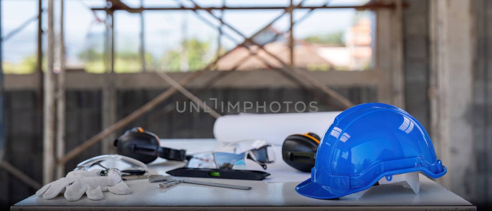 Engineer tool architecture blueprint design and safety helmet hardhat on meeting table with contractors paper project with engineer and architect working and discussing in background by nateemee