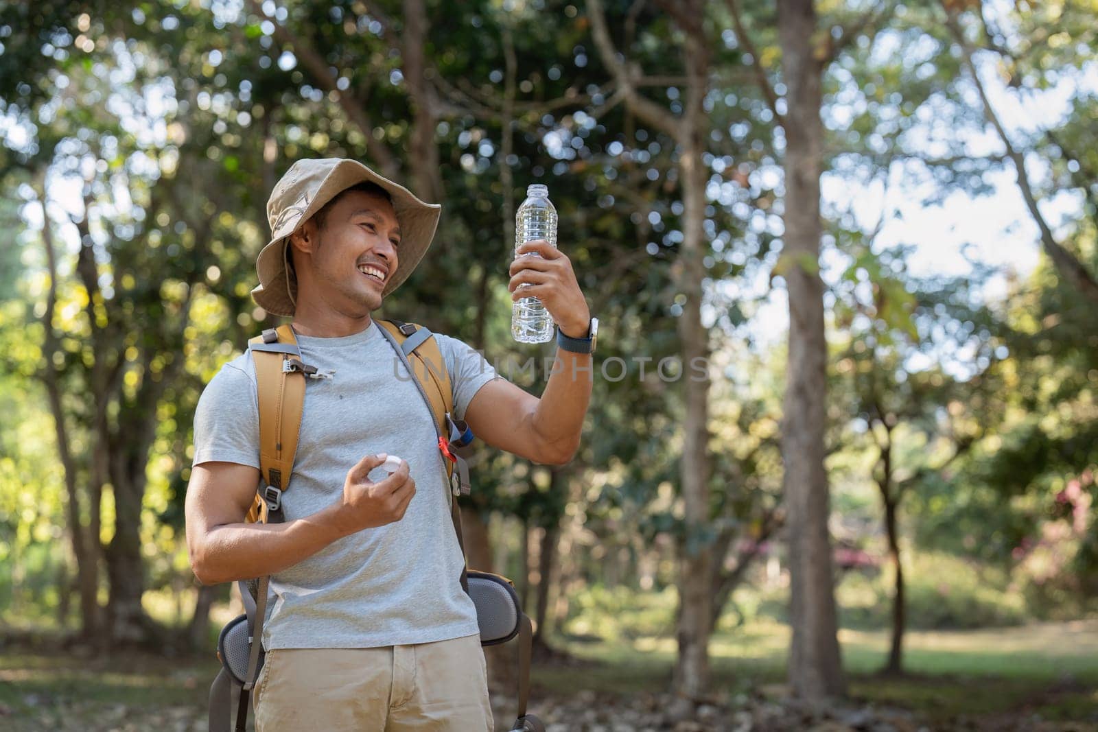 Traveler hiking man carrying a backpack on the back and walking in national park. man asian is rest by drink water by nateemee